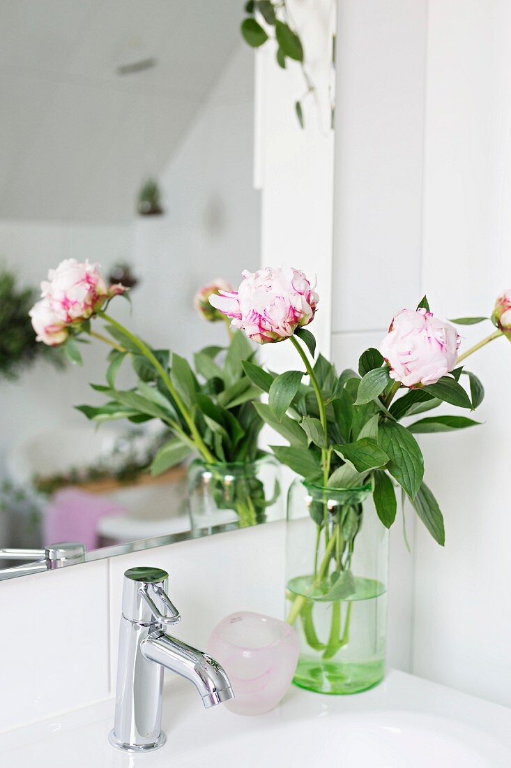 Bicolour peonies in glass vase on sink reflected in mirror