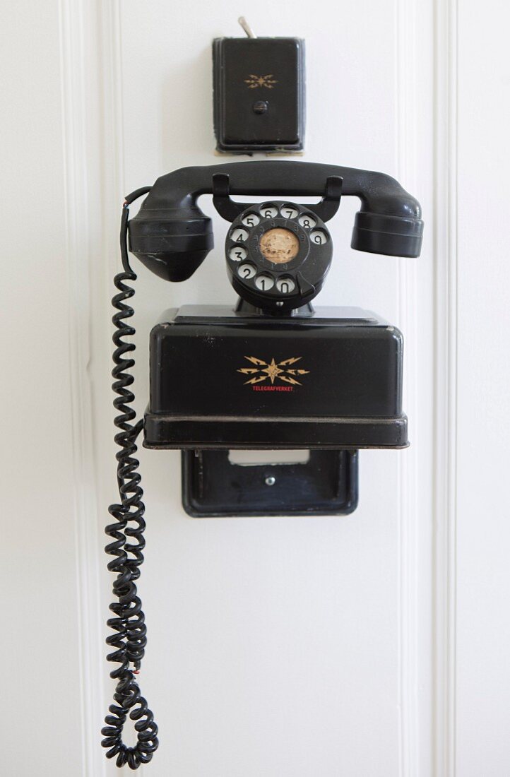 Schwarzes Vintage Telefon an weisser Holzwand aufgehängt