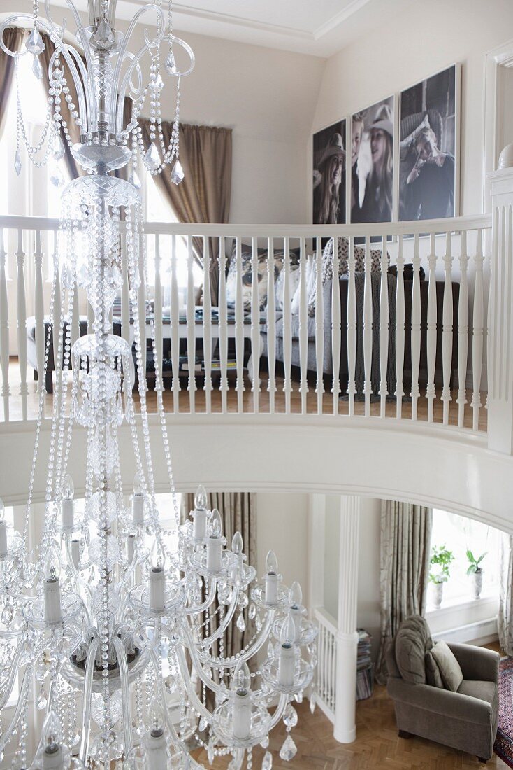 View from gallery with white wooden balustrade of Venetian-style, glass chandelier
