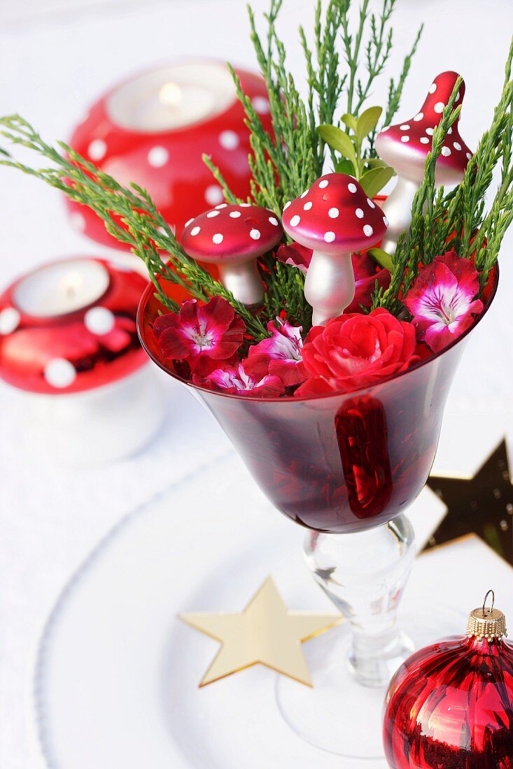 Weihnachtliche Deko aus Rosen, Geranienblüten & Deko-Fliegenpilze in Glaspokal