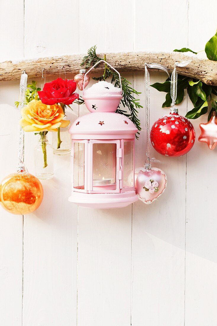 Festive arrangement of lantern, roses & baubles on wall