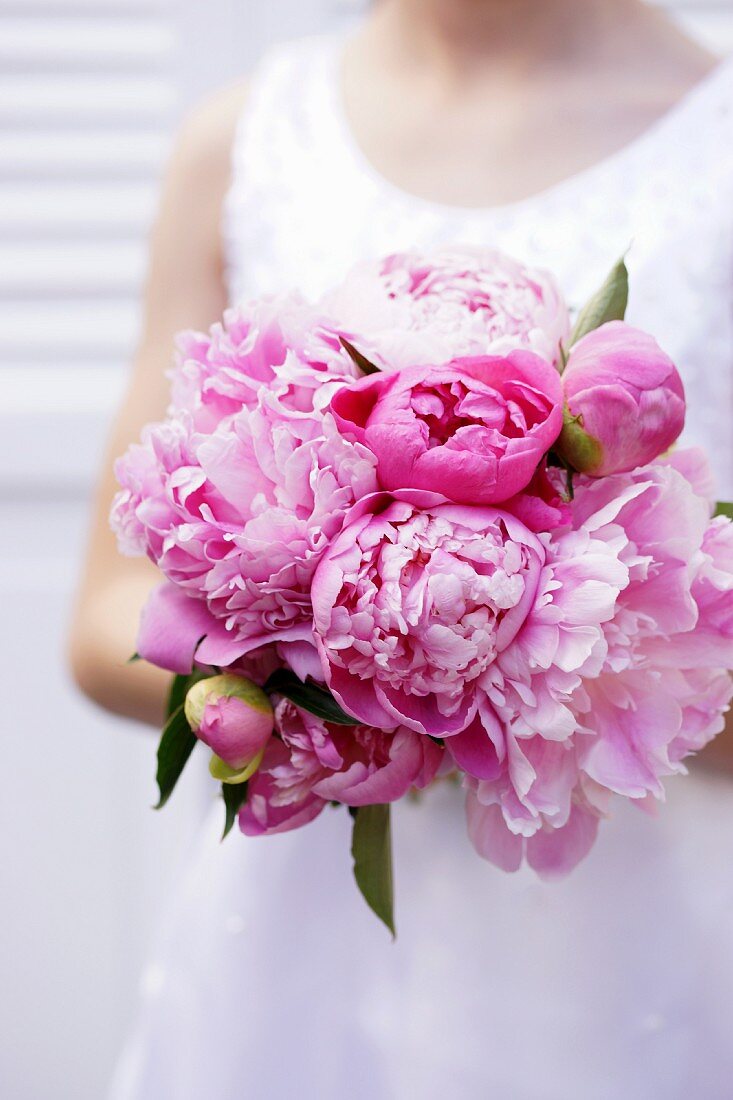 Girl holding bouquet of pink peonies