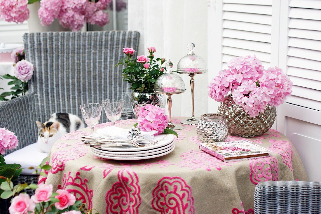 Table on terrace decorated with pink roses & mophead hydrangeas