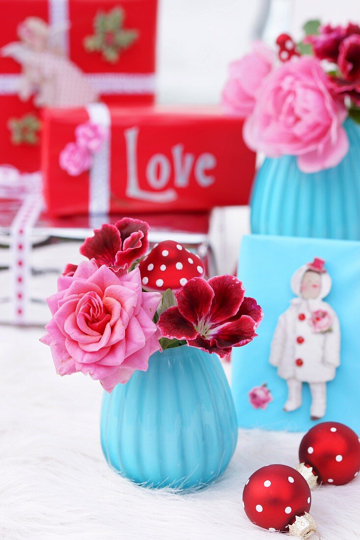 Weihnachtliche Dekoration in Blau & Rot mit Blüten in Vase, Christbaumkugeln & Geschenken