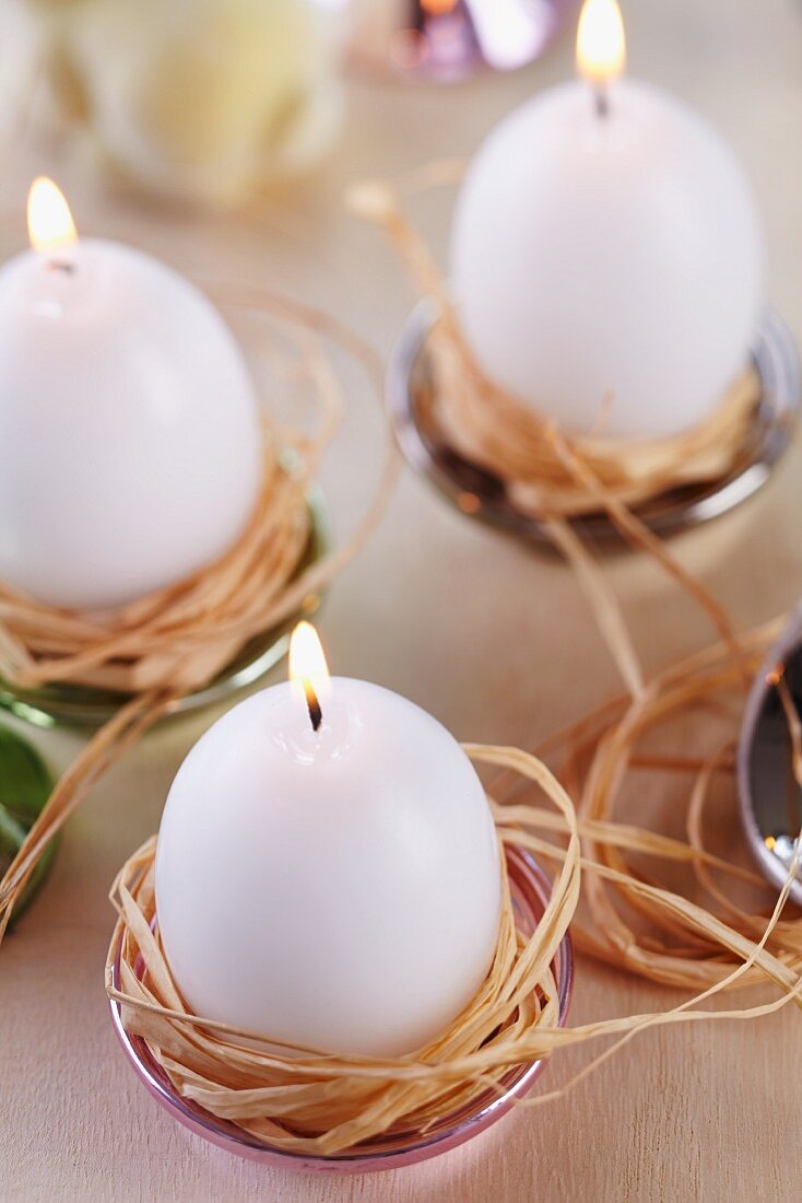 Kerzen in Ostereierform in kleinen Schalen als Kerzenständer mit Naturbast als Nest & Halterung