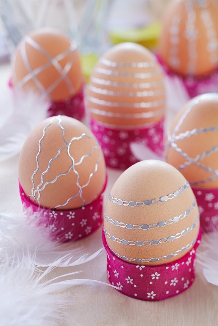 Braune Eier in selbstgemachten Eierbechern streifenmusterartig dekoriert mit silberfarbenen Aufklebern