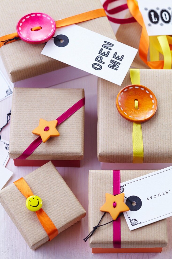 Gift boxes with brown paper lids decorated with buttons, ribbons & tags