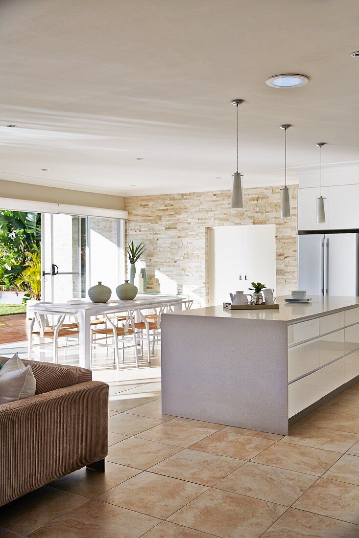 weiße Kücheninsel mit Schubladen vor Essplatz in modernem Wohnraum mit Fliesenboden