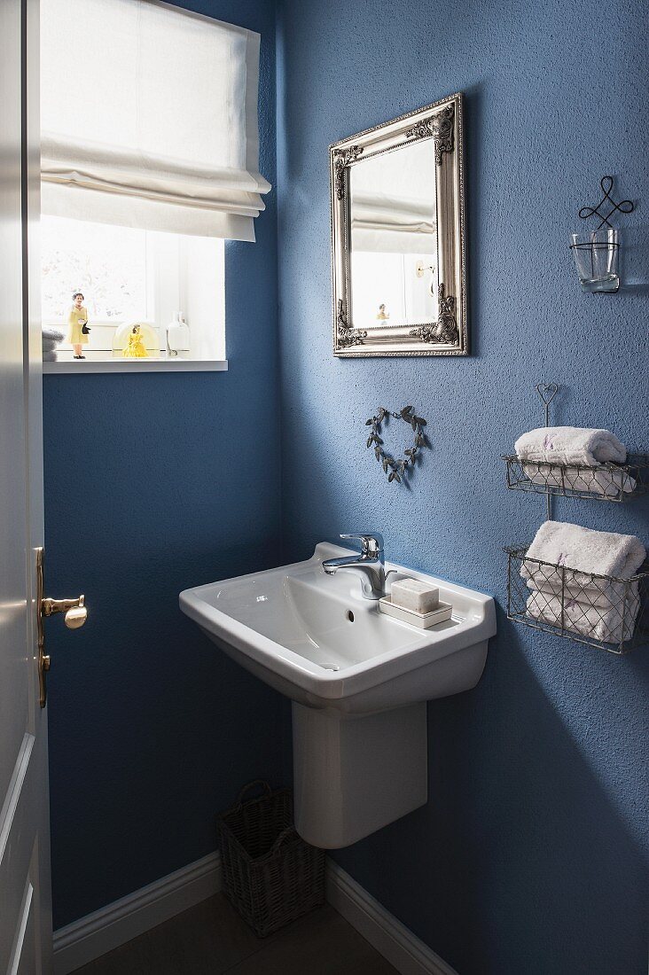 Washbasin and towel rack mounted on blue-painted bathroom wall