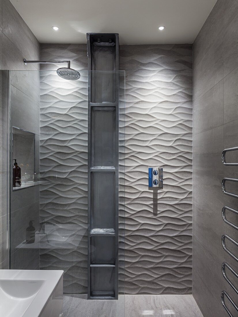 Designer bathroom - shower area with glass screen, tall metal shelves against tiled wall with 3D structured surface