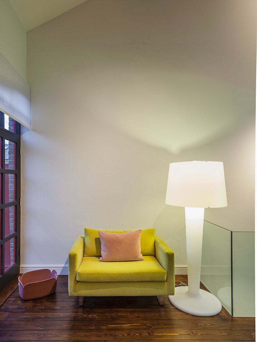 Gelber Designersessel und weiße Kunststoff Stehleuchte in Zimmerecke