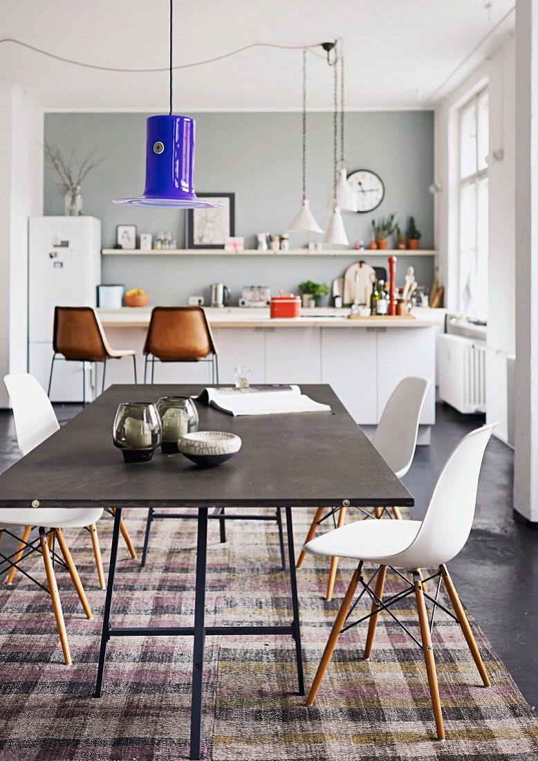 Blauer Murano Lampenschirm über schwarzem Tisch mit Plastic Chairs vor Küchentheke