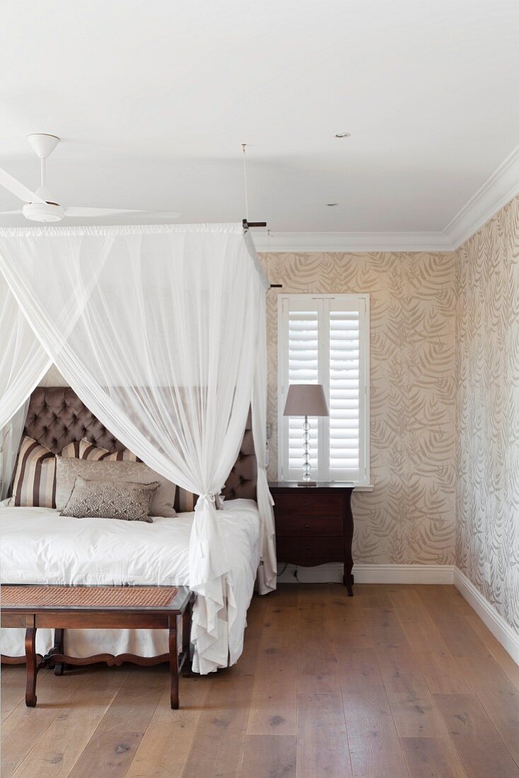 Bedroom with canopy, antique furniture and leaf-patterned wallpaper