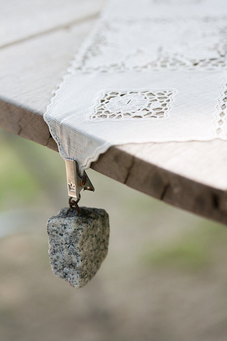 Tablecloth weight with granite pebble hung from lace tablecloth