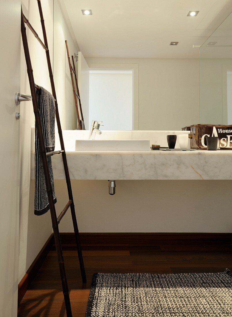 Handtuch-Leiter aus Bambus vor Marmor-Waschtisch mit Spiegelfront