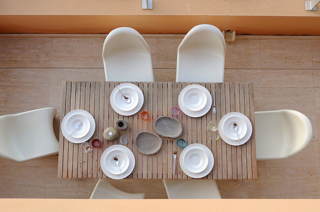 Vogelperspektive auf Terrasse mit einfach gedecktem Holztisch und Pantonstühlen