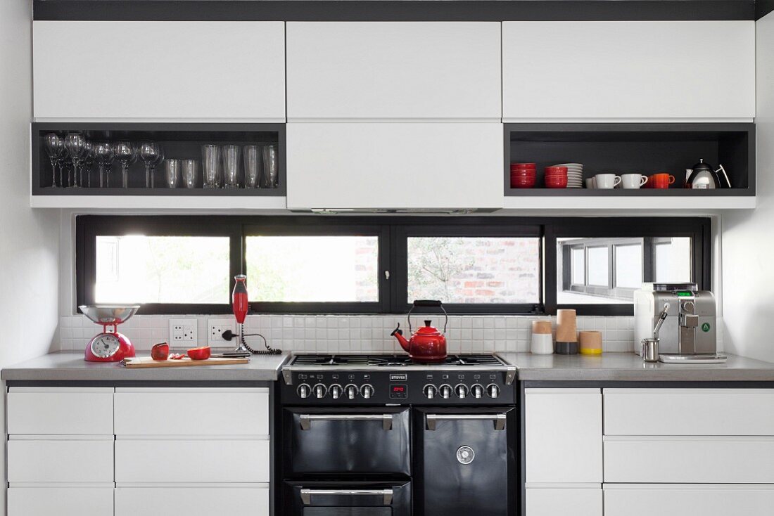 Moderne Einbauküche mit weissen, grifflosen Tip-On Fronten und schwarzen Akzenten durch Regaleinsätze und Fensterrahmen