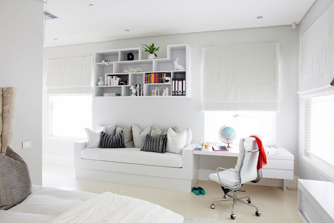 Fitted couch and desk as space-saving solution below decorative wall-mounted shelves in white, teenager's bedroom