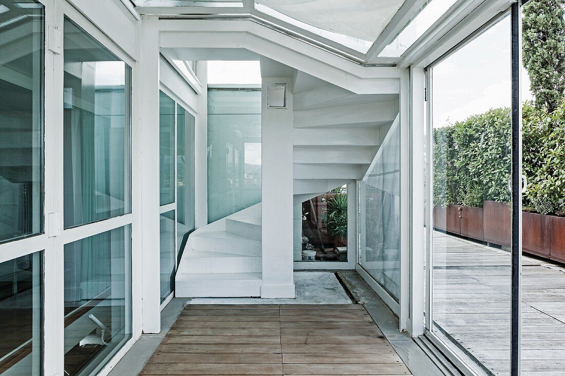 Porch of contemporary penthouse with terrace; staircase in background behind glass panel