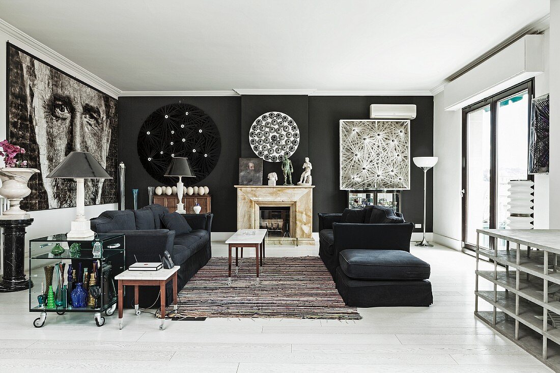 Schwarze Sofagarnitur und zierlicher Couchtisch auf Teppichläufer in Loungebereich mit schwarz getönten Wänden, seitlich grossformatiges Portraitbild