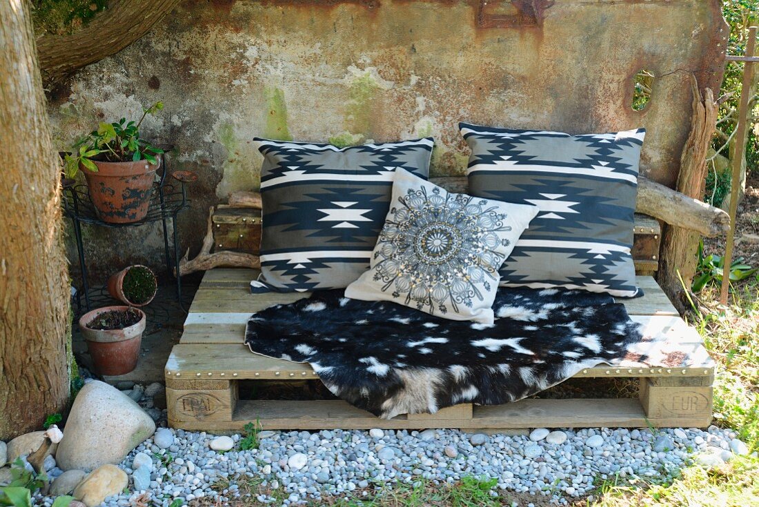Bench made from old wooden pallet with goat-skin rug and ethnic-style cushions