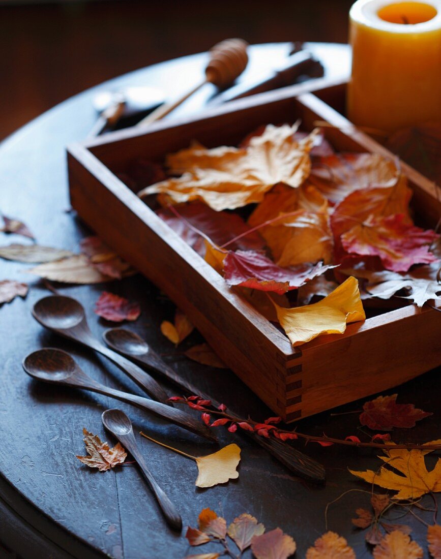 Herbstblätter in Holzkiste, daneben Holzlöffel