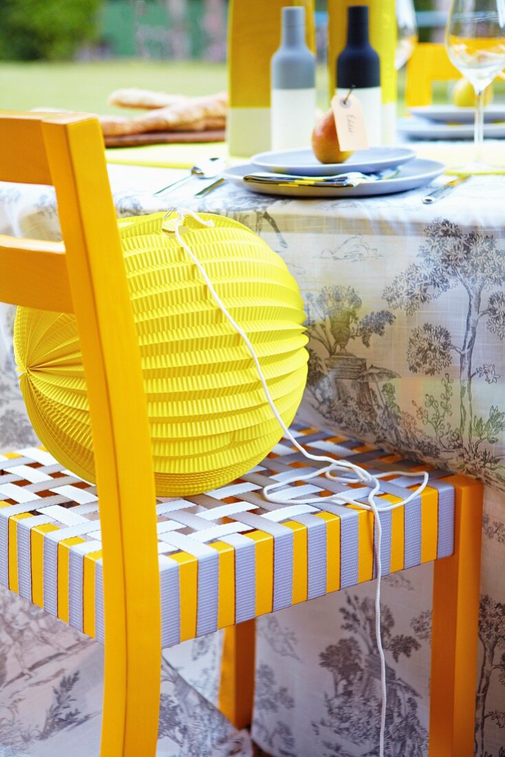 Papierlampion auf gelb-grauem Stuhl