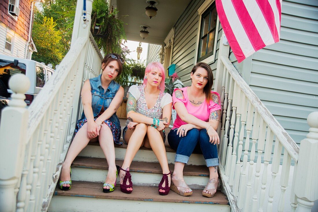 Drei junge Frauen auf Verandatreppe sitzend