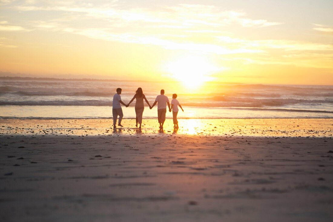 Familie geht händehaltend am Strand entlang (Cape Town, Südafrika)