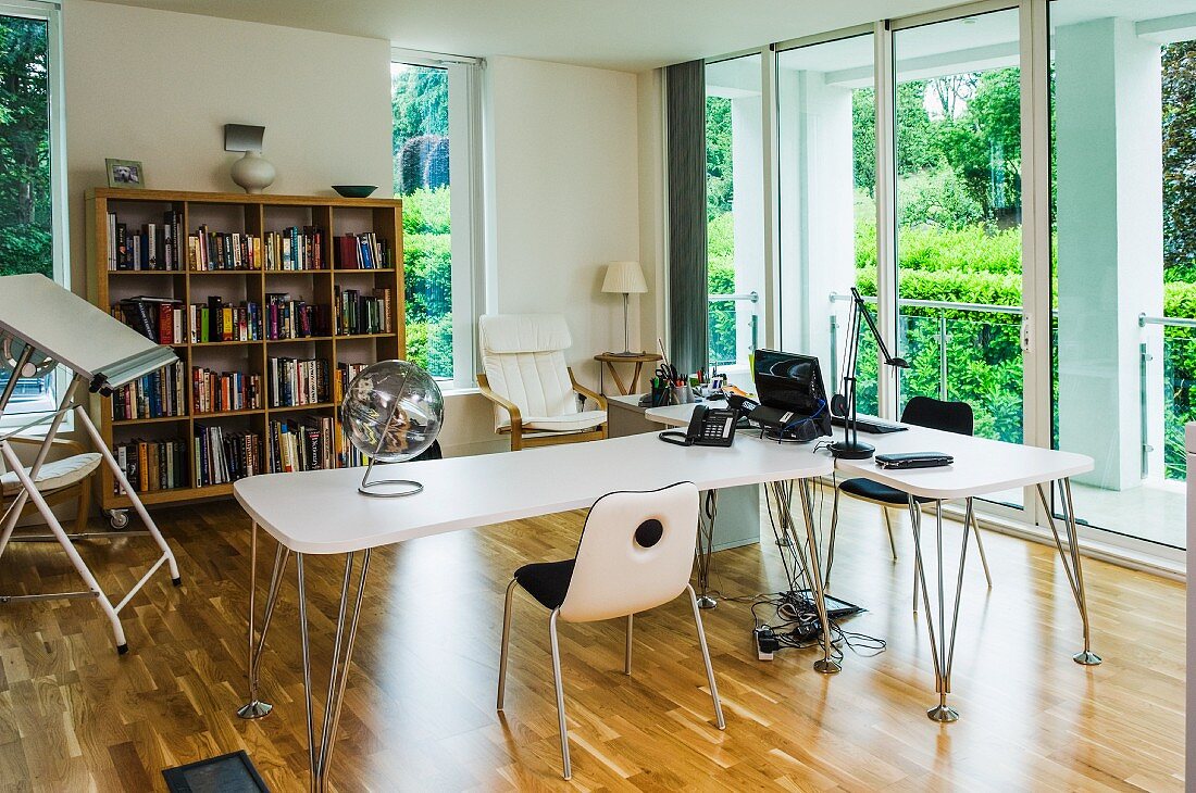 Bright office with designer desks, drawing table and glass sliding doors