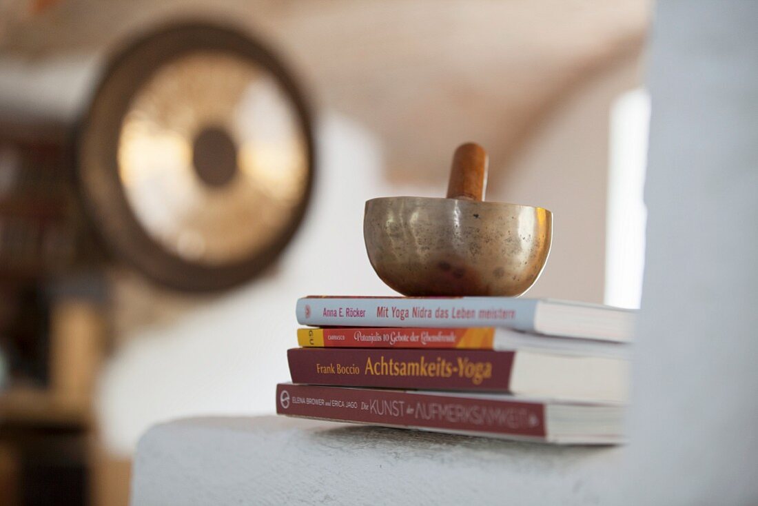 Singing bowl and striker on stacked books on masonry surface