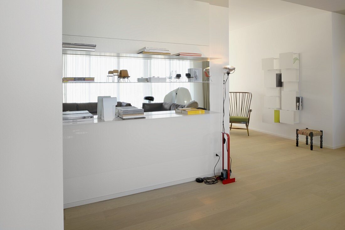 White partition with integrated shelves in spacious, bright interior; original wall-shelf and fifties armchair in background