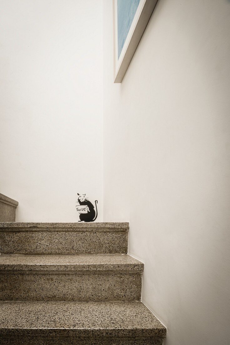 Terrazzo steps with small black animal stencilled on white wall