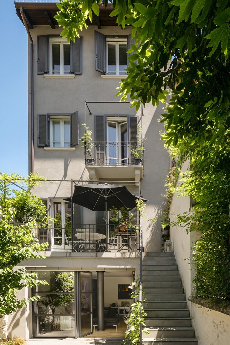 Traditional house with balconies and terrace; steps leading from courtyard to large balcony with grey parasol