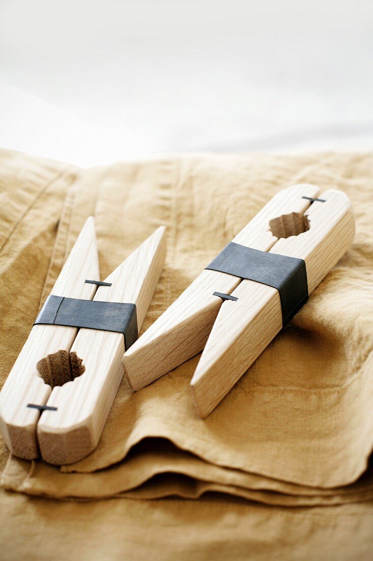 Two wooden pegs with metal clamps on pale brown linen