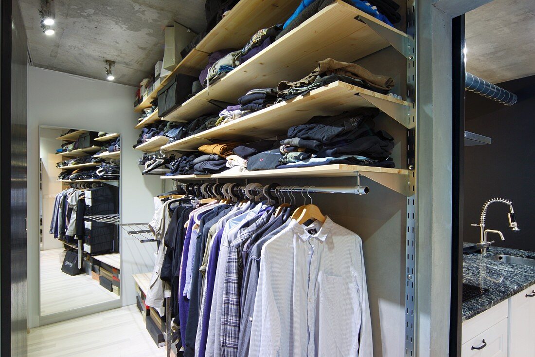 Ankleideraum mit offenem Schranksystem, auf Kleiderstange gehängte Hemden, oberhalb Ablagen
