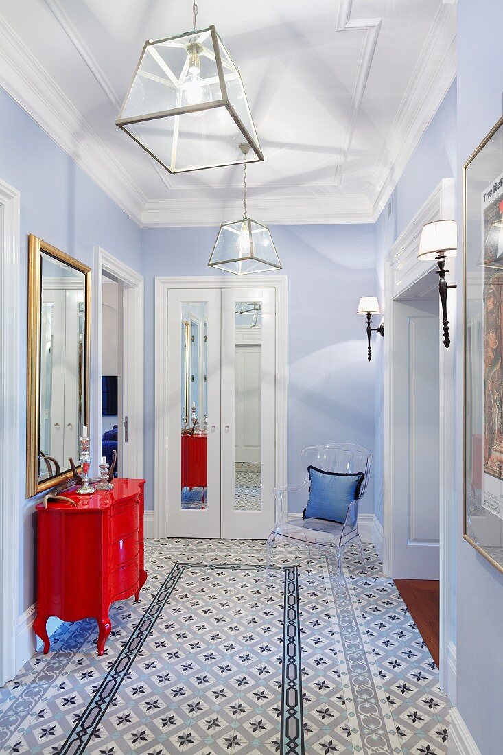 Flur mit gemustertem Fliesenboden, hellblauen Wänden, roter Kommode in postmodernem Stil