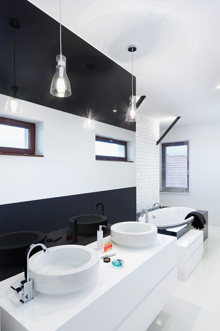 Weisser Waschtisch mit zwei Becken vor schwarz-weiss gestreifter Wand, in Designerbad