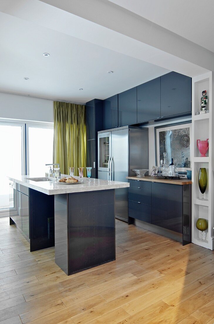 Modern, grey fitted kitchen with free-standing sink unit and ornaments on fitted shelves in frame of wide, open doorway