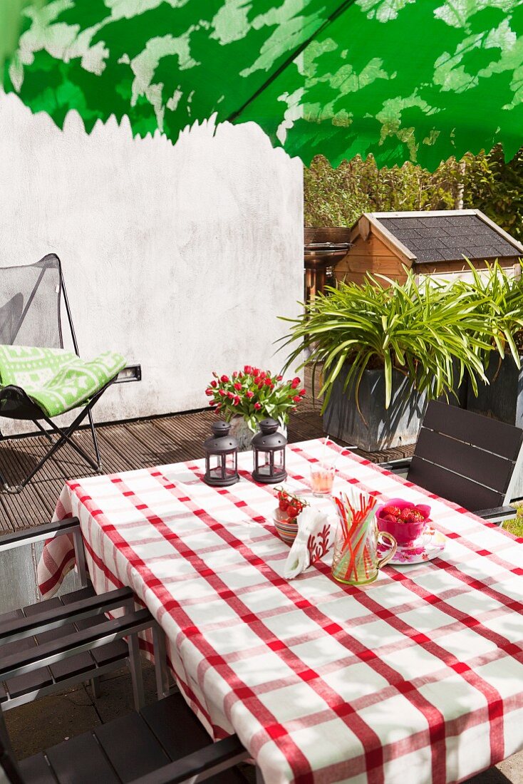 Table with red and white gingham tablecloth and outdoor chairs on terrace