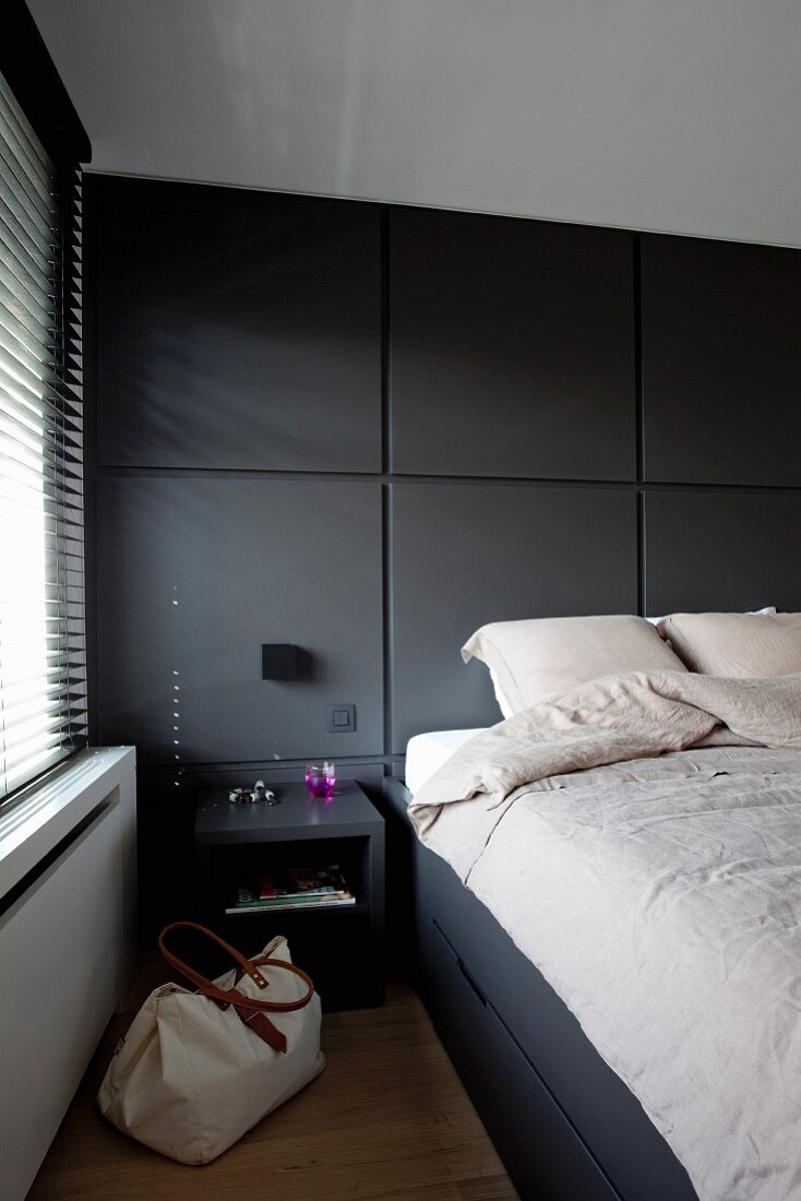 Schlafzimmer mit Doppelbett und dunklen Einbauten, seitlich Fenster mit Jalousien