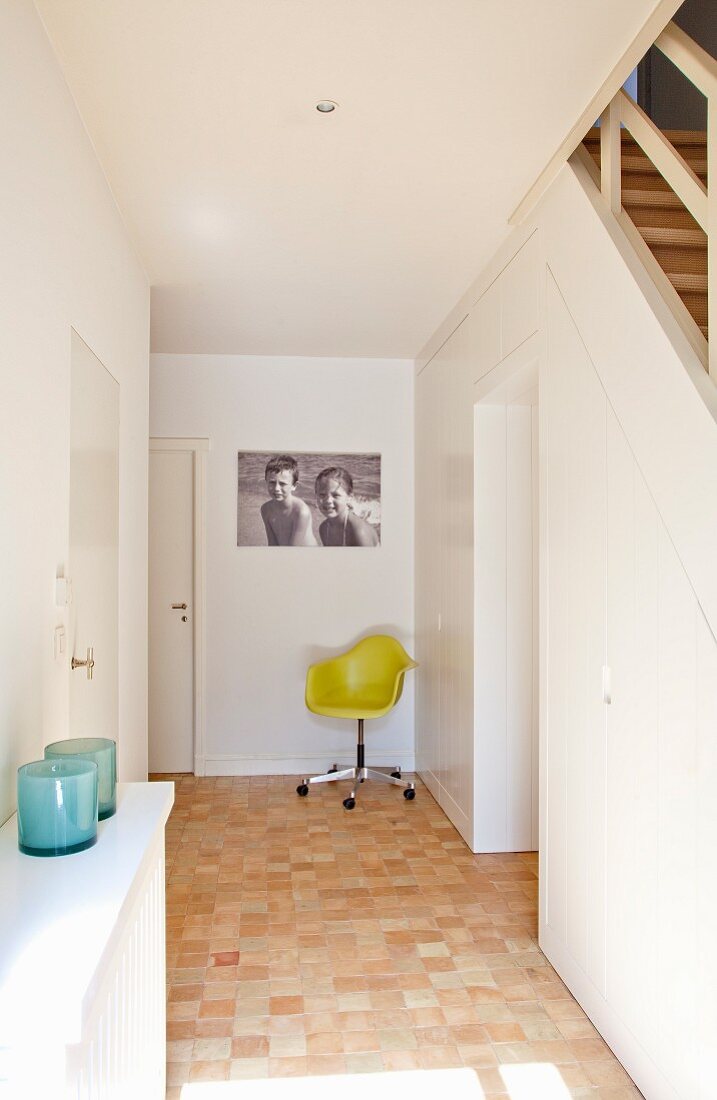 Hallway with black and white holiday photo of children above classic, yellow shell chair