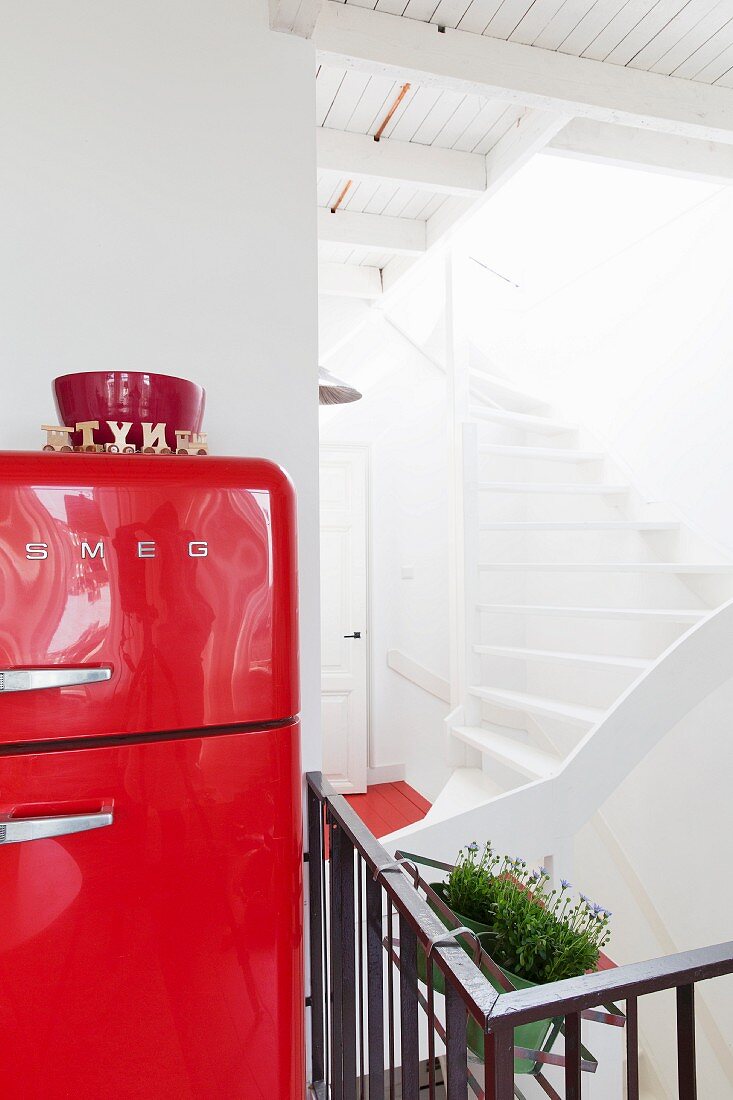 Red-painted, retro fridge and view into stairwell with white treads