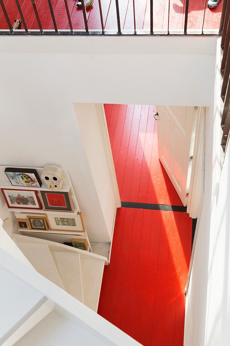Blick von oben auf durchgehenden, rot lackierten Dielenboden in offenem Treppenhaus