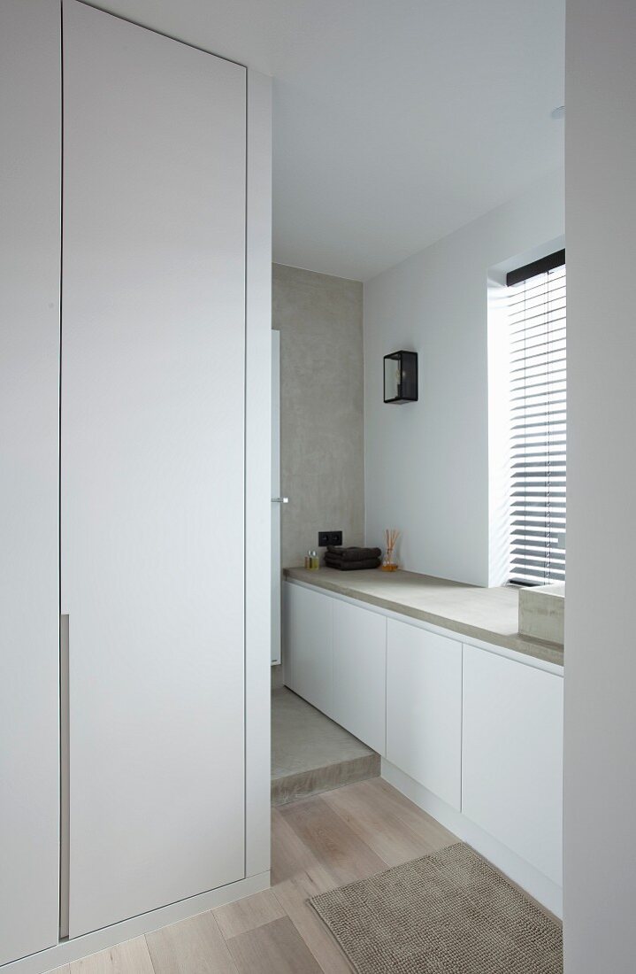 Purist bathroom with white, fitted cabinets, concrete elements and wooden floor
