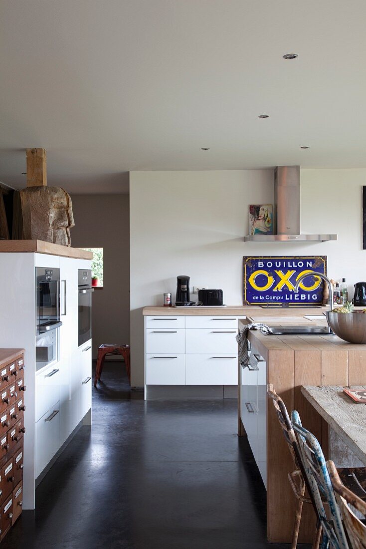 Open-plan kitchen with modern cupboard elements and fitted appliances in renovated country house belonging to artist