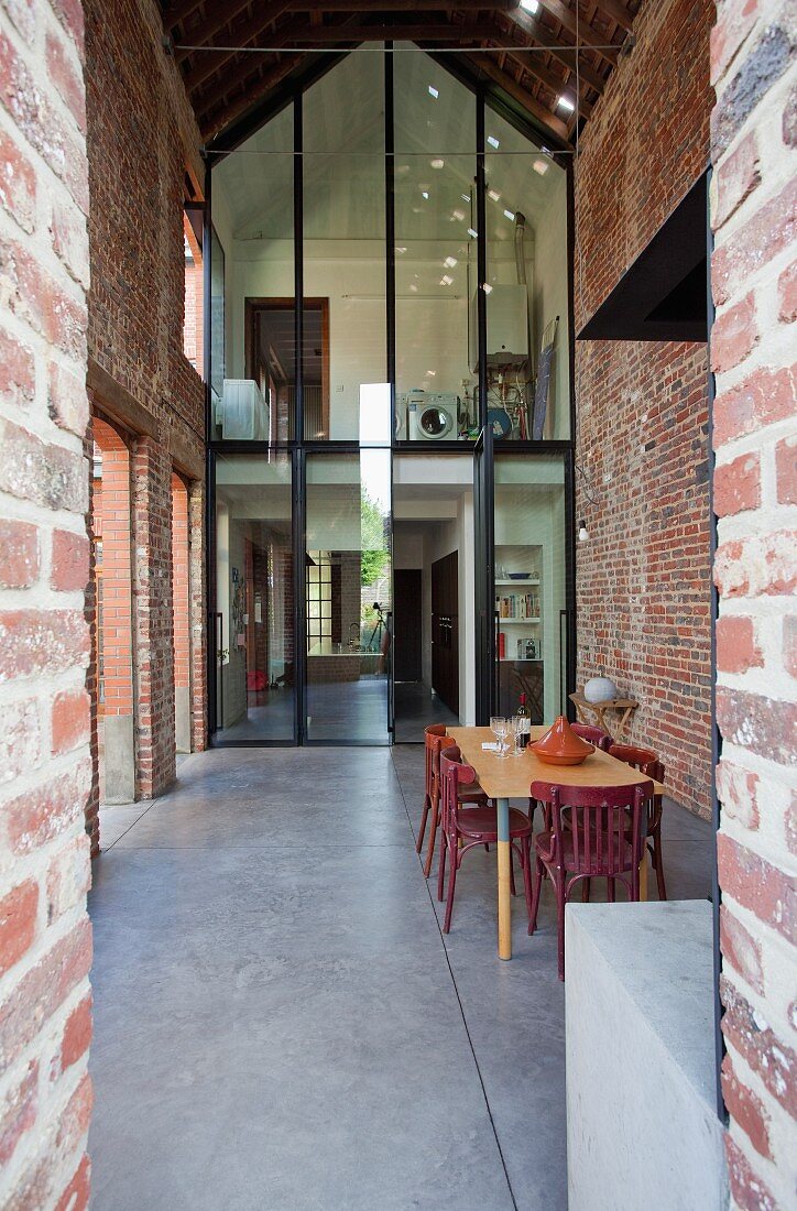 Dining area with tall brick walls and two-storey glass wall with steel frame