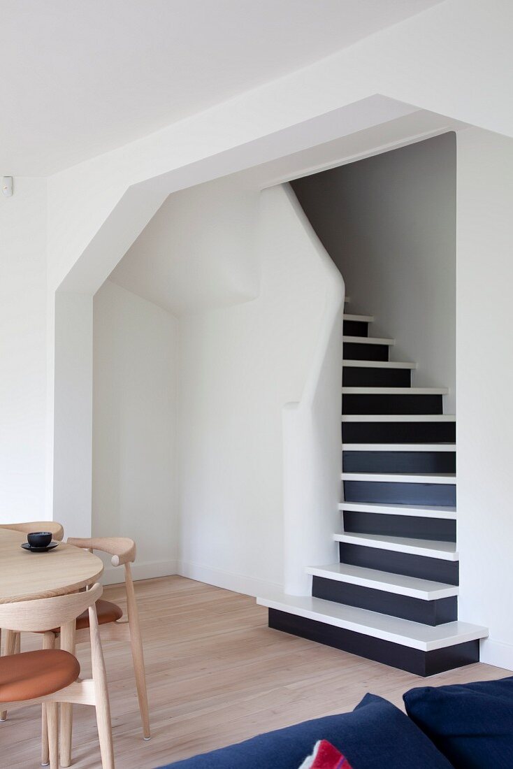 Foot of staircase with black risers and white treads seen through wide, open doorway