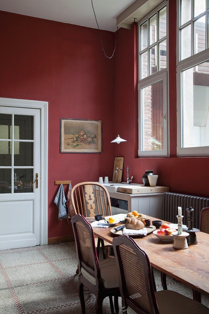 Traditionelle Küche, Wände bordeauxrot getönt und antike Stühle um Esstisch