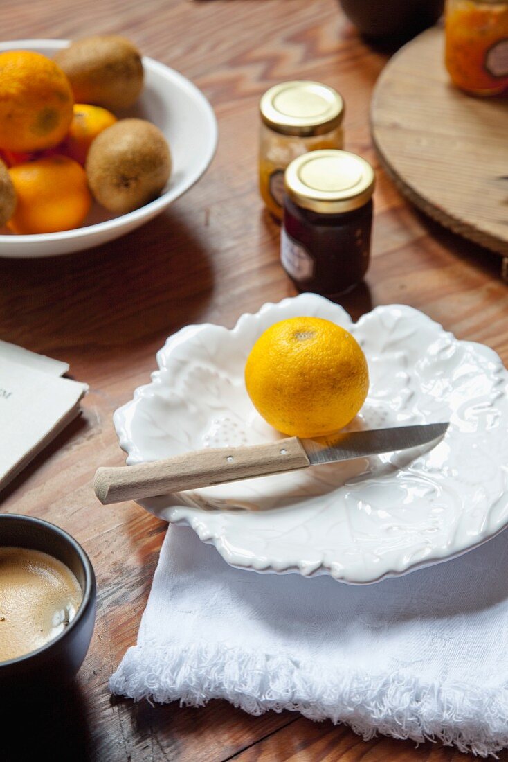 Fresh lemon and knife on white, leaf-shaped plate